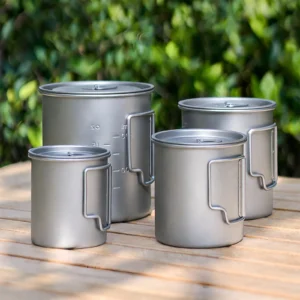 TA1 titanium folding handle mugs with lids displayed outdoors on a wooden table in four sizes.