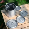 TA1 titanium folding handle mugs nested together with separate lids shown on a wooden table.