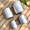 Top view of four TA1 titanium folding handle mugs arranged on a wooden table.
