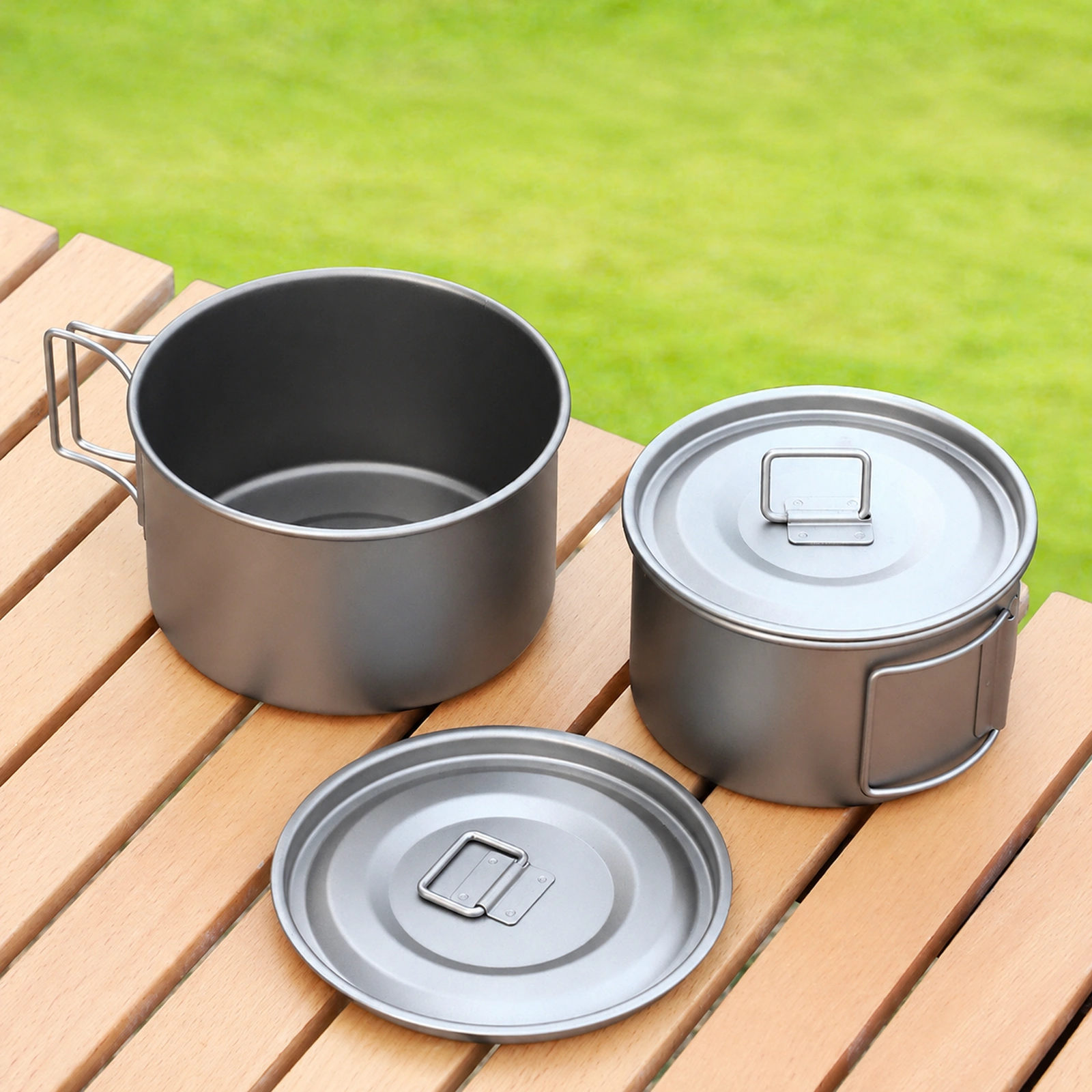 TiRoam titanium camping pot cookware set with lid and folding handle on an outdoor table, lightweight titanium gear for camping and backpacking.