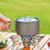 TiRoam titanium camping pot with lid and folding handle on a camp stove, lightweight cookware for outdoor cooking and backpacking meals.