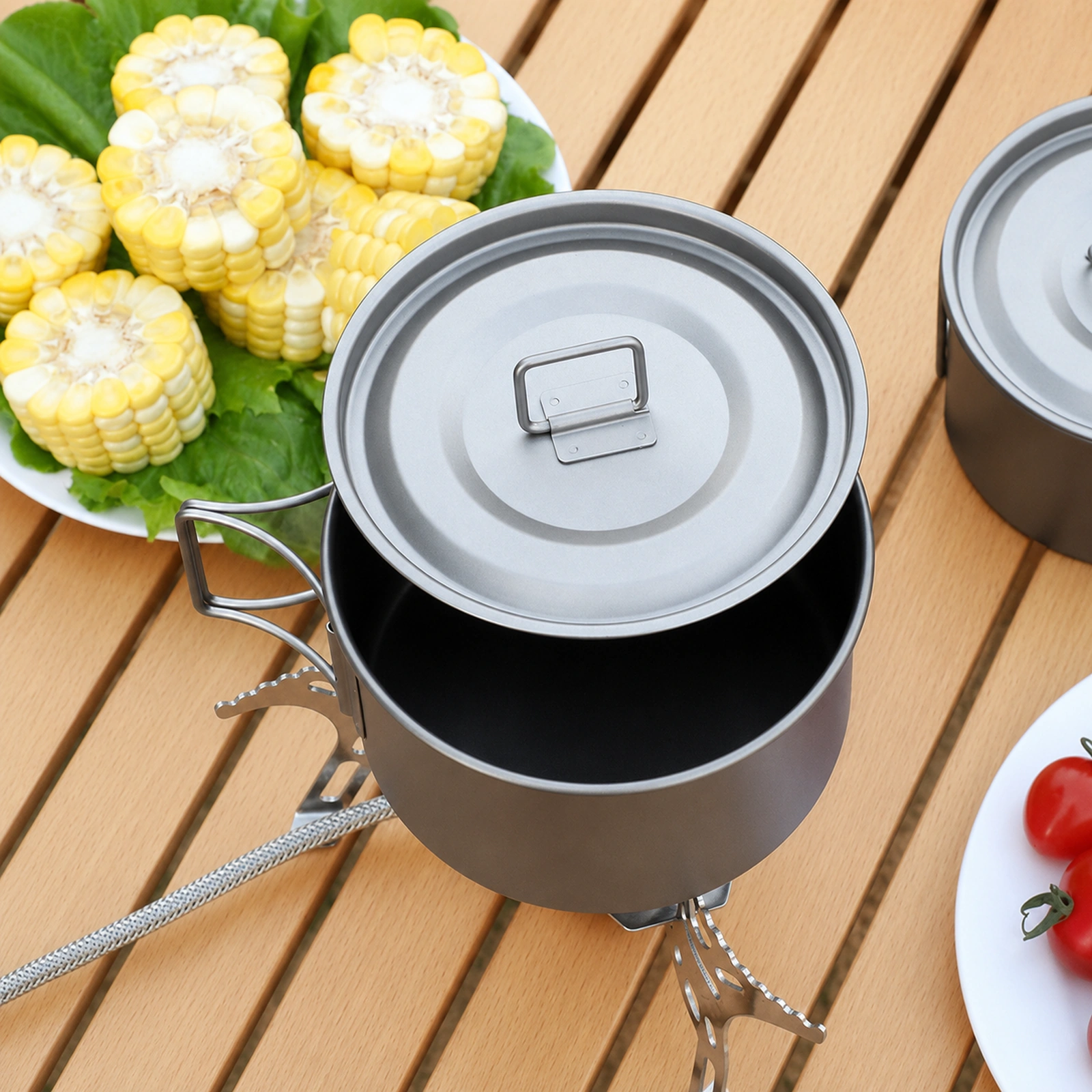 TiRoam titanium camping pot with open lid on a wooden camping table, lightweight outdoor cookware for camp cooking, picnics, and travel meals.