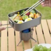 TiRoam titanium lunch box cooking on a portable camp stove, rectangular titanium cookware with folding handle for outdoor cooking and camping meals.