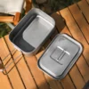TiRoam titanium lunch box with open lid on a camping table, lightweight rectangular titanium cookware for camp meals, storage, and outdoor food prep.