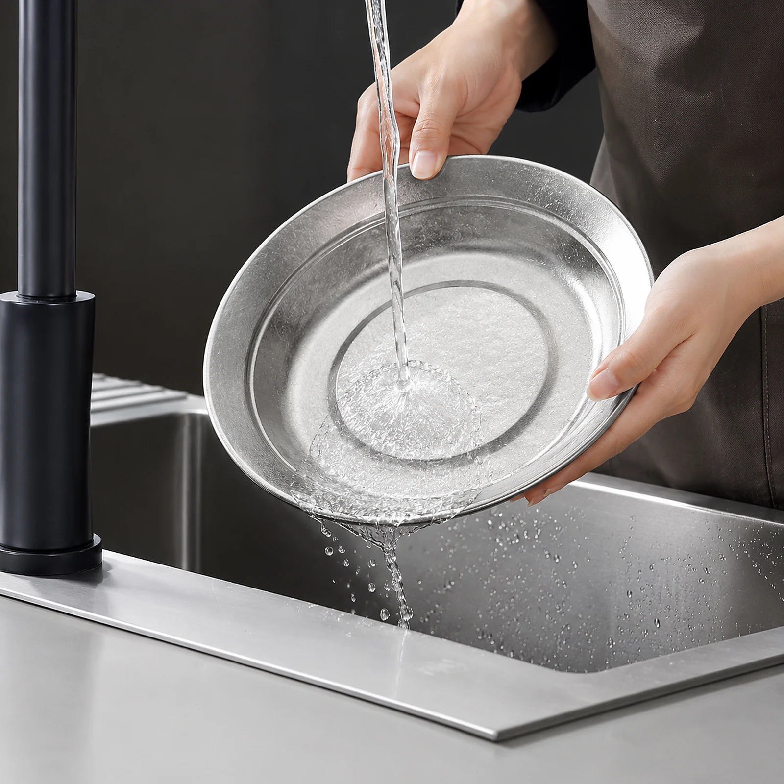 TiRoam pure titanium plate being rinsed under running water in a kitchen sink, easy-clean reusable titanium dinnerware for home, camping, and outdoor use.