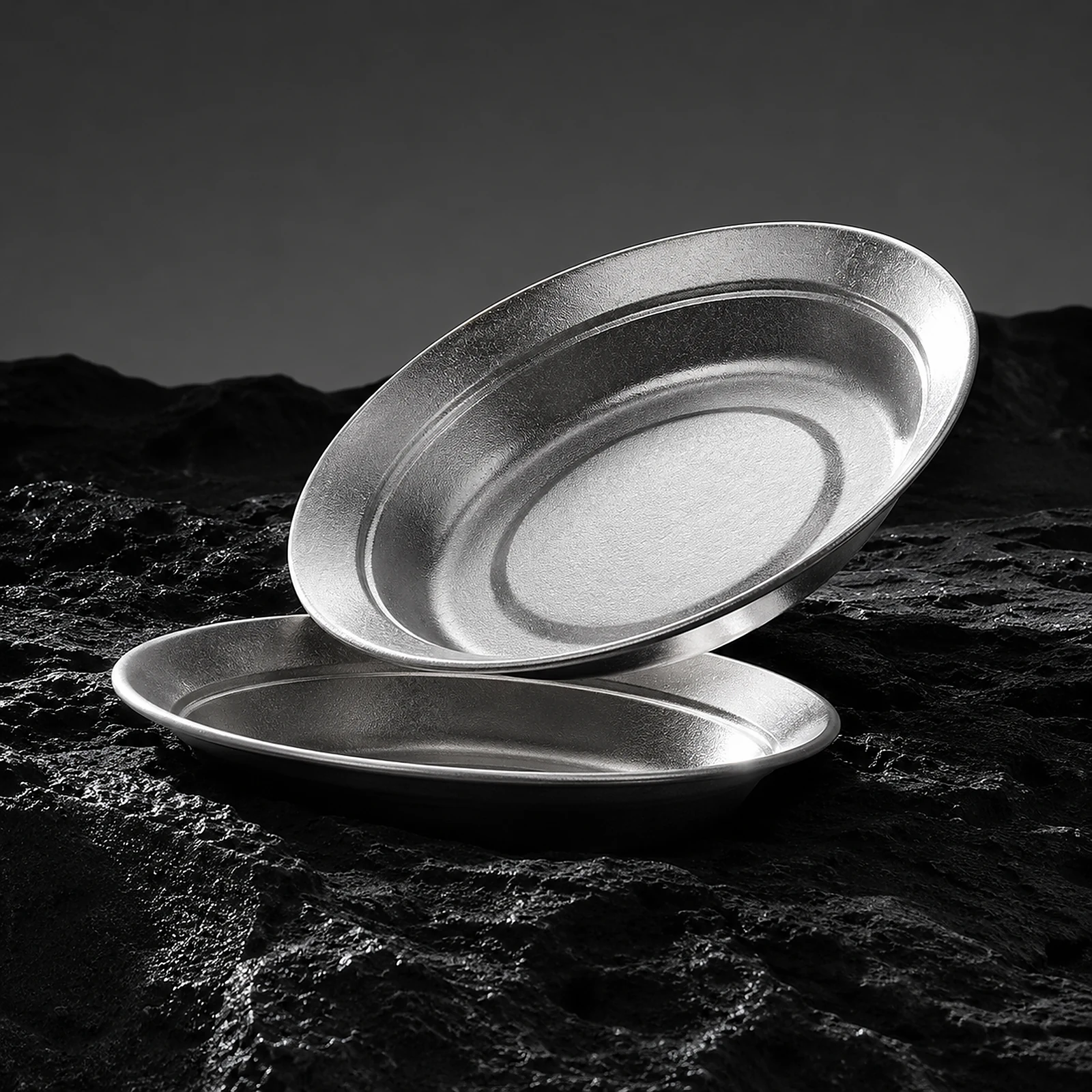 Two TiRoam pure titanium plates displayed on dark rock texture, durable lightweight titanium dinnerware for outdoor dining, camping, and minimalist tableware.