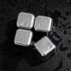 TiRoam titanium whiskey stones on a wet black surface, reusable chilling cubes for whiskey, cocktails, bourbon, and cold drinks without watering them down.