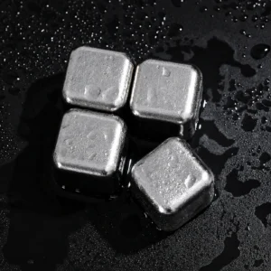 TiRoam titanium whiskey stones on a wet black surface, reusable chilling cubes for whiskey, cocktails, bourbon, and cold drinks without watering them down.