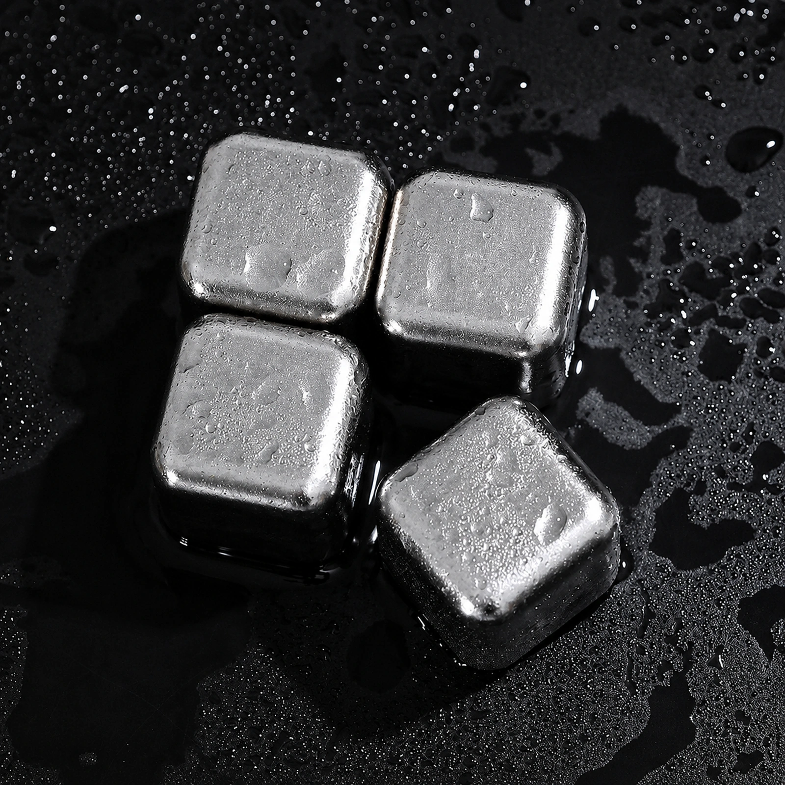 TiRoam titanium whiskey stones on a wet black surface, reusable chilling cubes for whiskey, cocktails, bourbon, and cold drinks without watering them down.