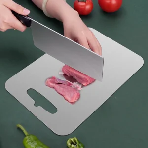Flat pure titanium cutting board used for cutting fresh meat with a kitchen knife.