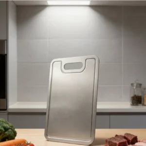 Grooved pure titanium cutting board displayed upright in a modern kitchen.
