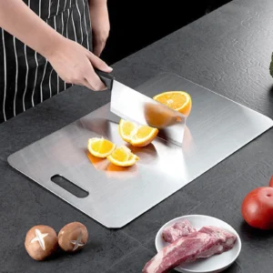 Pure titanium cutting board used for slicing fresh oranges during kitchen food prep.