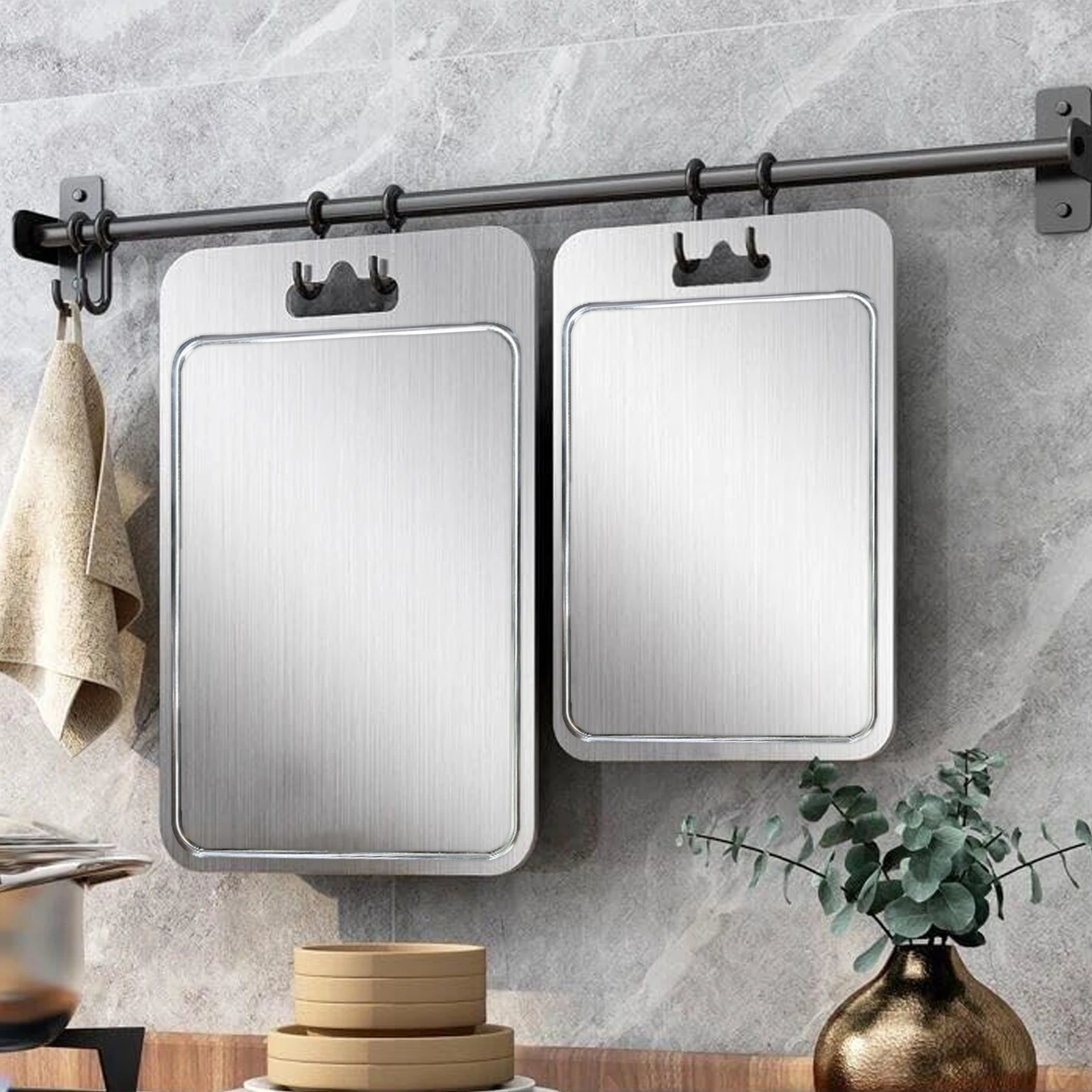 Two grooved pure titanium cutting boards hanging from a kitchen rail for convenient storage.