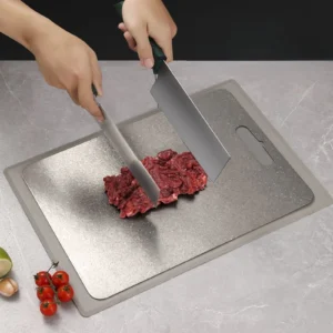 Pure titanium cutting board used for preparing fresh meat on a kitchen counter.