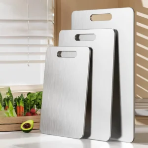 Three sizes of pure titanium cutting boards displayed upright in a bright kitchen.