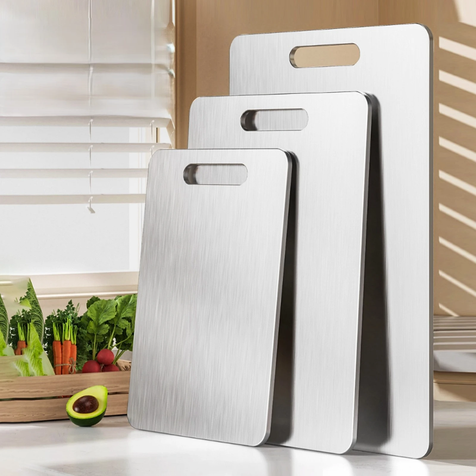 Three sizes of pure titanium cutting boards displayed upright in a bright kitchen.