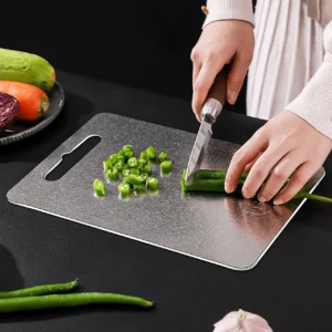 Pure titanium cutting board used for chopping fresh green vegetables in the kitchen.