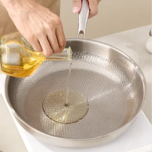 Cooking oil being poured into a titanium frying pan before cooking