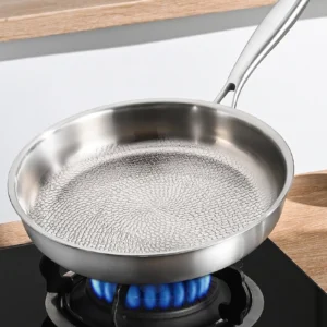 Titanium frying pan with hammered cooking surface over a gas flame