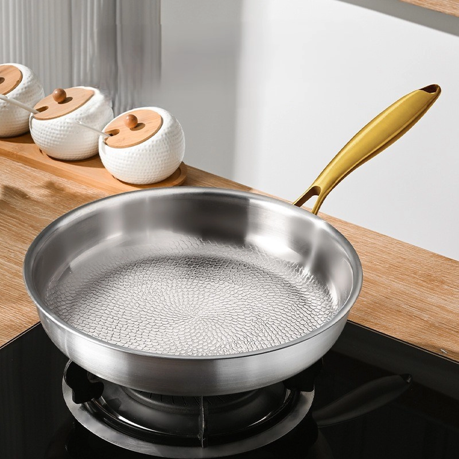 Titanium frying pan with gold handle and hammered cooking surface on stovetop