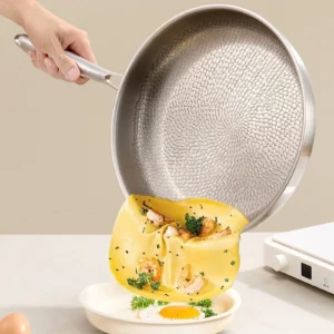 Omelet sliding from a titanium frying pan onto a plate
