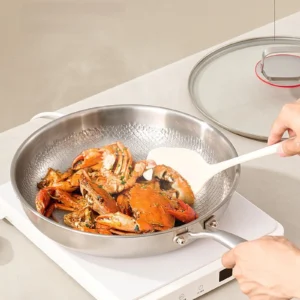 Seafood being cooked in a titanium frying pan on an electric cooktop