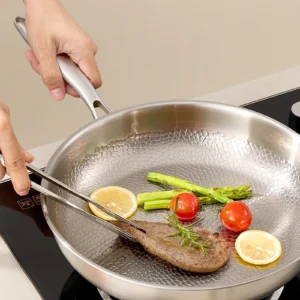 Steak asparagus tomatoes and lemon cooking in a titanium frying pan
