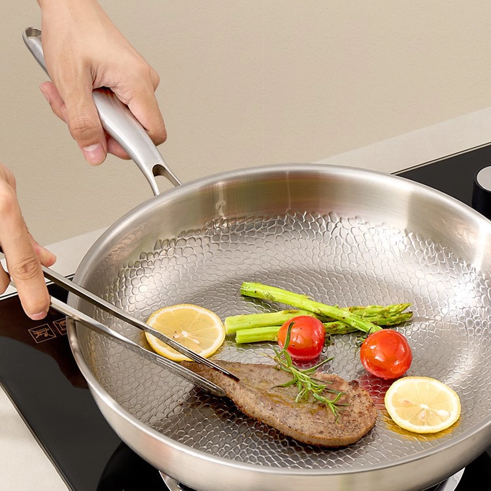Steak asparagus tomatoes and lemon cooking in a titanium frying pan