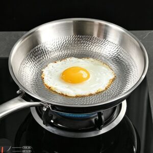 Fried egg cooking on the dragon-scale textured surface of a titanium frying pan.
