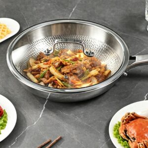 Titanium frying pan with a stainless steel and glass lid covering a prepared meat and vegetable dish.