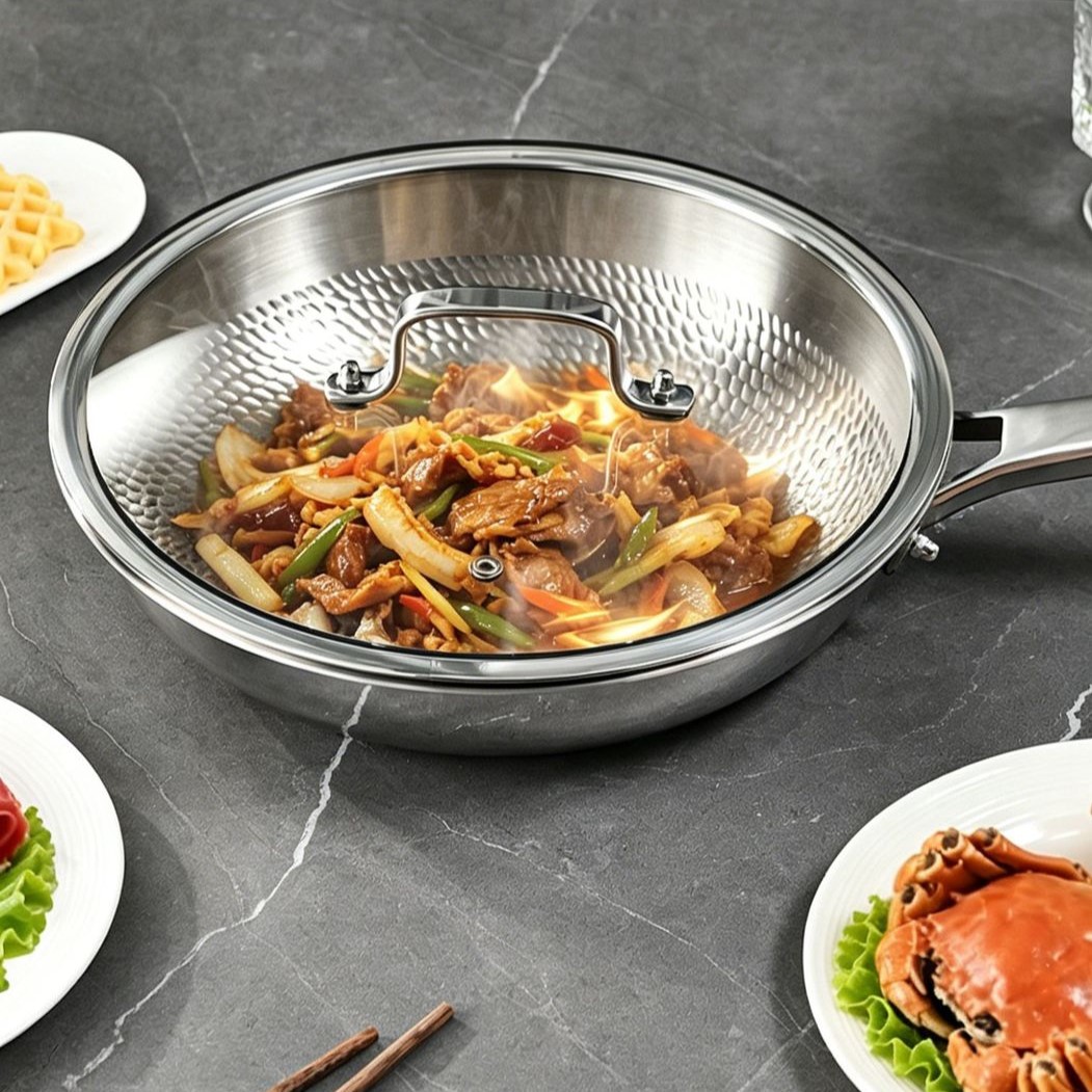Titanium frying pan with a stainless steel and glass lid covering a prepared meat and vegetable dish.