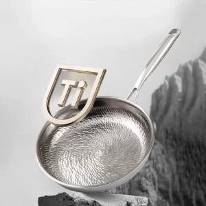 Close-up of a titanium frying pan highlighting its embossed cooking surface and stainless steel handle.
